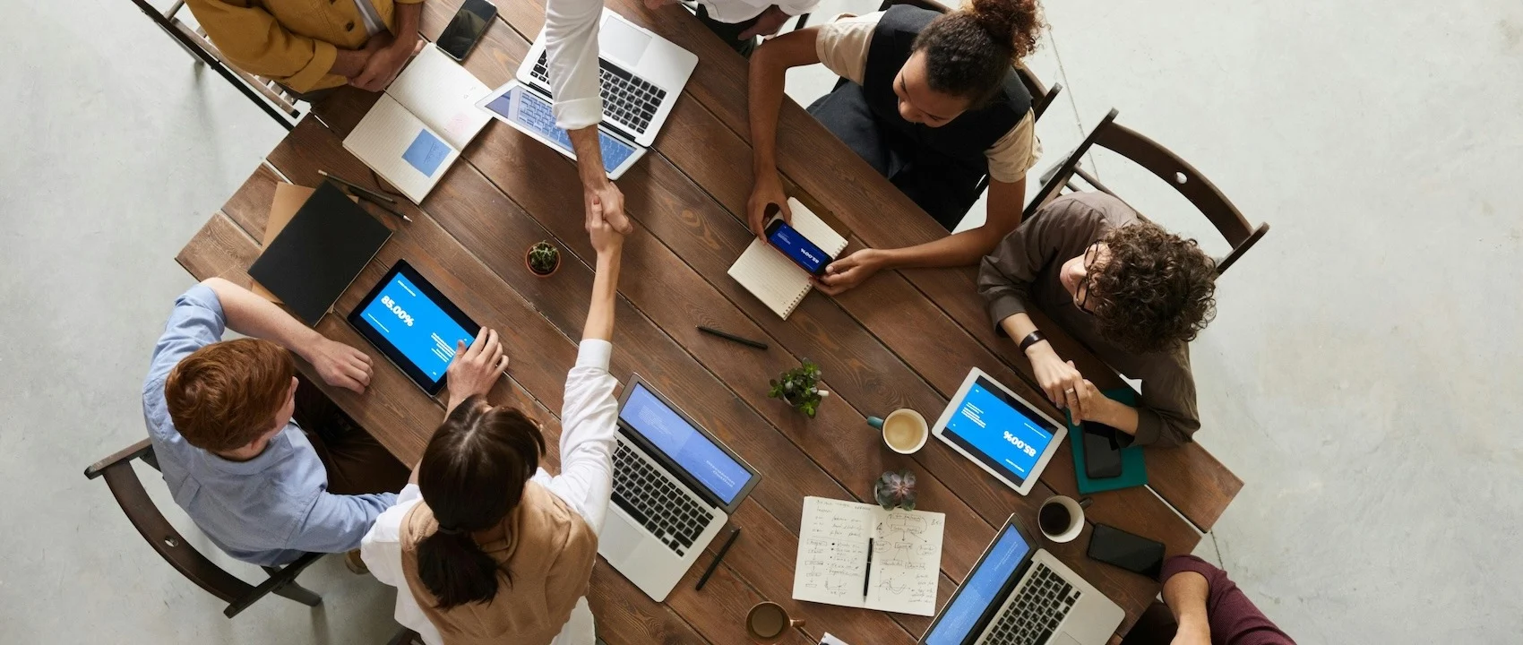 Equipo de profesionales colaborando en torno a una mesa con dispositivos y herramientas de trabajo